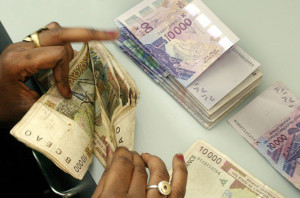 A Senegalese bank teller counts a pile of old 10 000 CFA Franc notes (Approximately 15 Euros) to be replaced with the new 10 000 CFA Franc notes seen above as part of a massive campaign