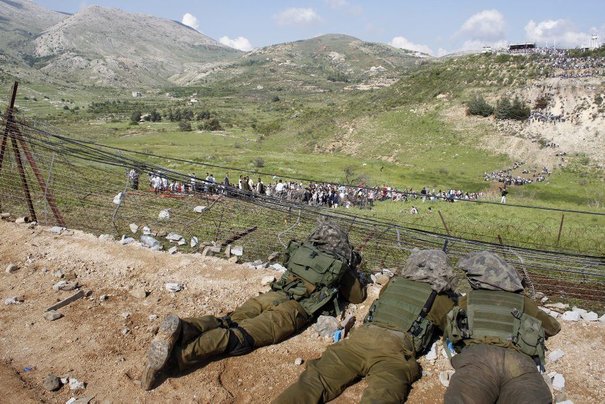 Israeli soldiers lie in their position during a demonstration by Syrian protesters marking Nakba near Majdal Shams in the Golan Heights